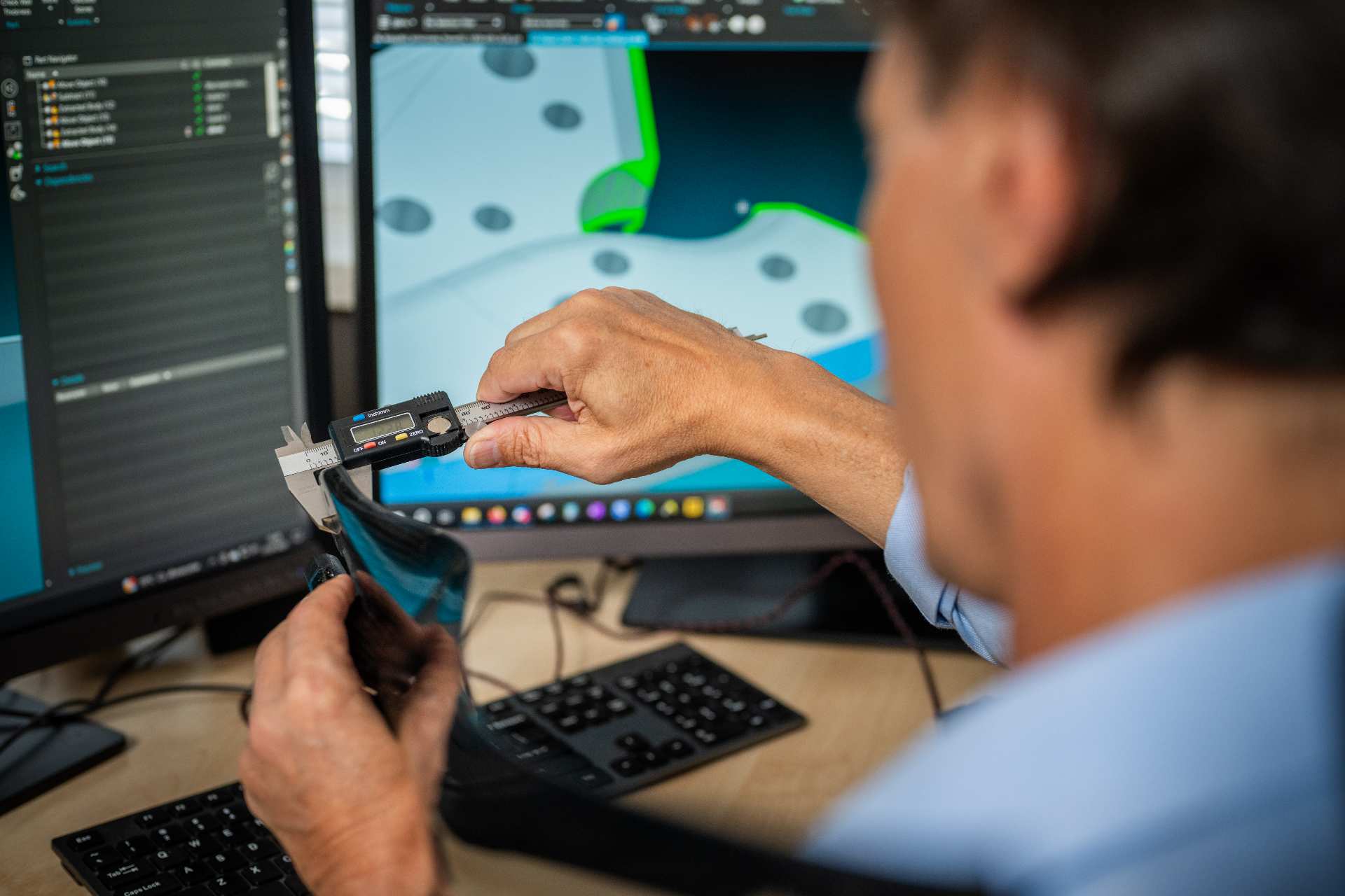 Widok z tyłu na mężczyznę, który mierzy element podczas pracy nad prototypem produktu.